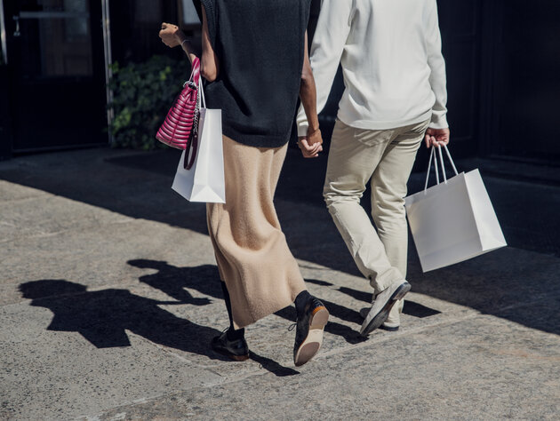 Man and woman holding hands while walking on a sidewalk with shopping bags