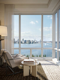A serene living room with a white armchair overlooking the view of a blue river from the corner window
