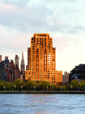 A grand apartment building on a river highlighted with orange sunlight