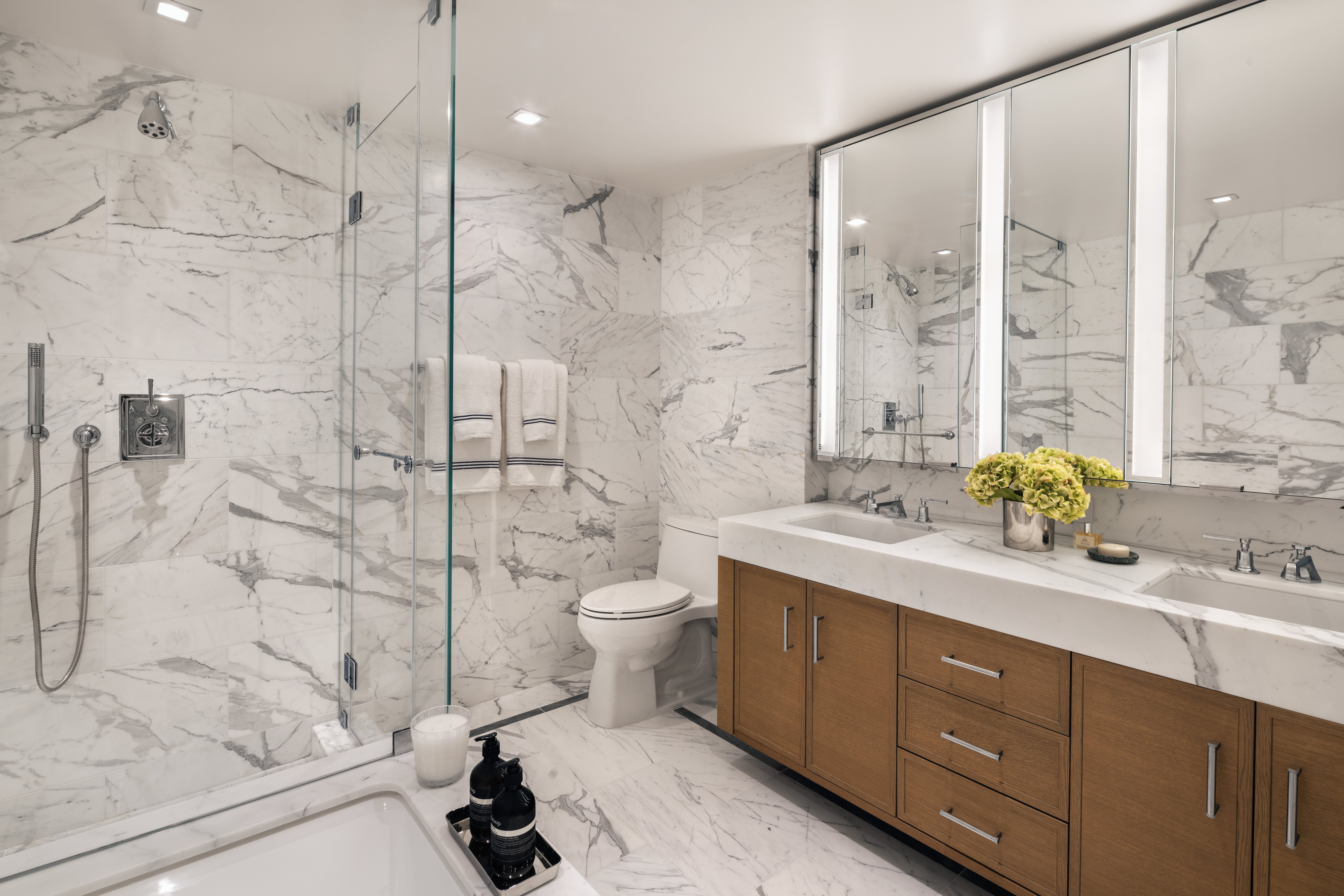 primary bathrooms with white marble and custom oak vanities
