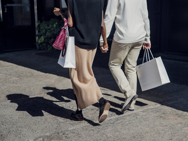 Man and woman holding hands while walking on a sidewalk with shopping bags